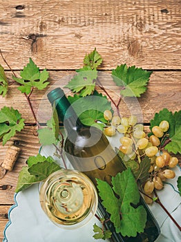White wine glass and bottle and fresh grapes on wooden background