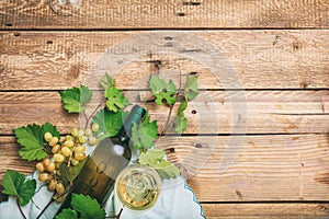 White wine glass and bottle and fresh grapes on wooden background, copy space