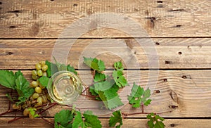 White wine glass and fresh grapes on wooden background, copy space