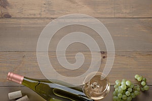 White wine in a glass, grapes, cork, opener and bottle on the table