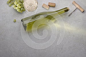 White wine in a glass, grapes, cork, opener and bottle on the table