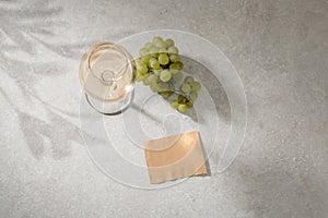 White wine in a glass, grapes and a label for your text on the table