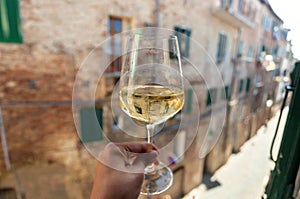 White wine glass in hand of italian person, living in historical Siena city, Tuscany. Leisure in Italy