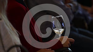 White wine in a glass in the hands of a girl in red. close-up