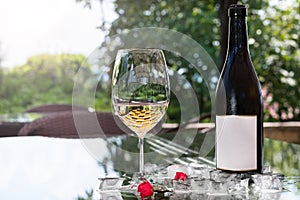 White wine in a glass with ice, old wooden background, selective focus