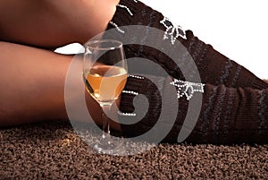 White wine glass and woman legs on carpet floor