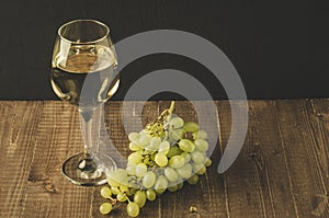 White wine and grape/wineglass with white wine and grape on a wooden table, selective focus
