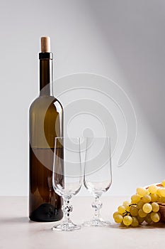 White wine and grapes. White wine in bottle, two empty glasses a