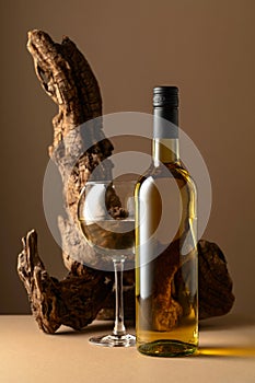 White wine and old snag on a beige background