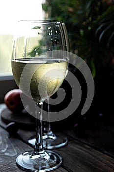 White wine is poured into glasses. There are fruits nearby