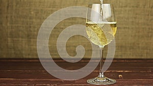 White wine pouring into glass on wooden table