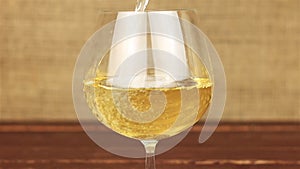 White wine pouring into glass on wooden table