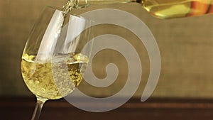 White wine pouring into glass on wooden table