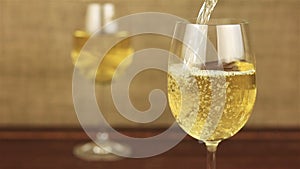 White wine pouring into glass on wooden table