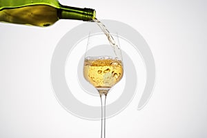 White wine pouring from green bottle, close up.