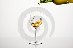 White wine pouring from green bottle, close up shot on white isolated background.