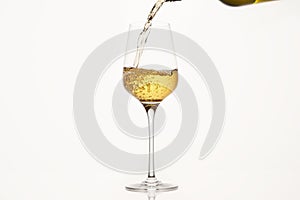 White wine pouring from green bottle on white isolated, close up.