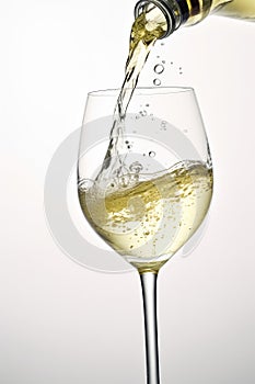 White wine pouring to glass from bottle on white background, created using generative ai technology