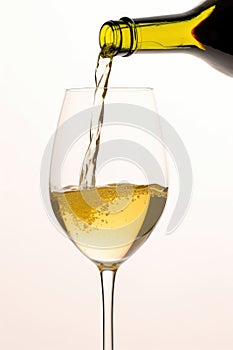 White wine pouring to glass from bottle on white background, created using generative ai technology