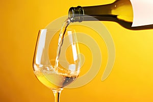 White wine pouring to glass from bottle on yellow background, created using generative ai technology