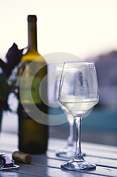 White wine served on a wineglass with other drinking glasses and a bottle of wine