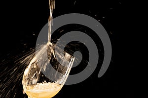 White wine splashing into a small glass goblet