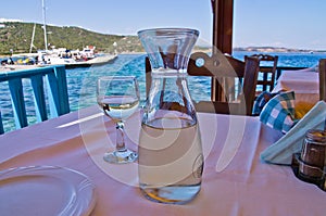 White wine on a table in a shade of a typical greek taverna by the sea