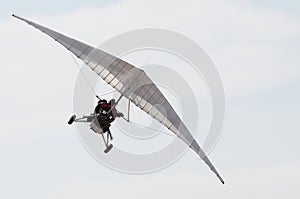 A white wing micro-light plane against thick white clouds