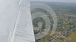 The white wing of a passenger plane against the top view of nature backdrop of a beautiful blue lake, flies over a pond