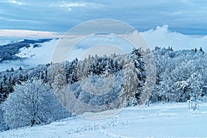 White winter landscape with clouds in valley of biosphere reserve Rhoen in Germany, frosty snowy mystic scene