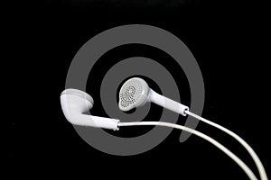 White wired earphones on black background.