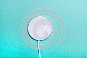 White wireless charging pad for smartphone on the green background.