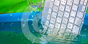 White wireless computer keyboard falling into the water spraying