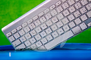 White wireless computer keyboard falling into the water spraying