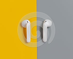 White wireless earphones on yellow and grey background