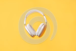 White wireless headphones against a yellow background