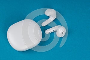 White wireless headphones. New earphones on blue background. New technologies