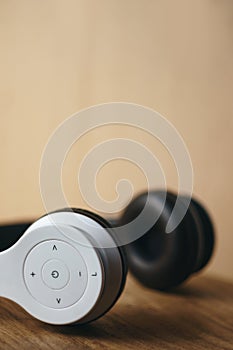 White wireless headphones placed on natural wooden surface on a blurred light wooden background