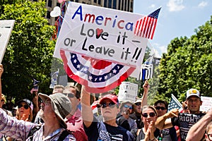 A Woman Holds a Sign Reading `America Love it Or Leave it` at a Conservative Rally