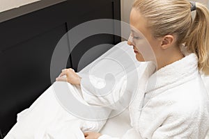 White Woman With Nasal Strip on Nose Getting Ready to Sleep, Sits on Bed and Hold Pillow
