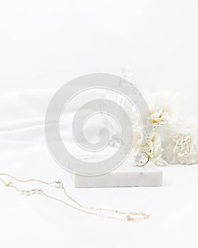 White women cosmetic desk decorated with marble white fabric golden ring necklace and flower