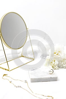 White women cosmetic desk decorated with marble white fabric golden round mirror ring necklace and flower