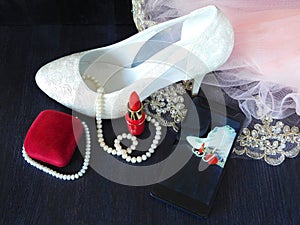 White women`s shoes with high heels, red lipstick, present box and smartphone with the photo in the screen