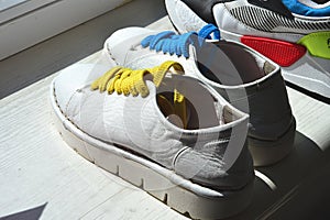 White women\'s sneakers with yellow and blue laces