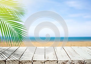 White wood table top with blur sea beach and coconut leaf.Holiday summer background