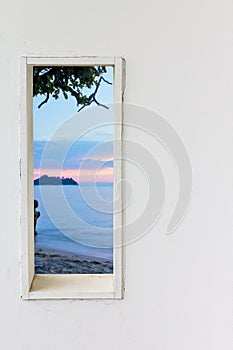 White wood wall window with sunset sea beach view.