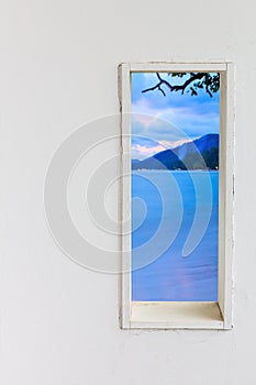 White wood wall window with sunset sea beach view.