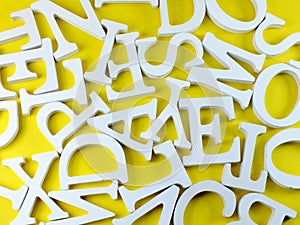 White wooden alphabet letters top view on yellow background