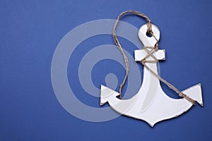 White wooden anchor figure on blue background, top view. Space for text