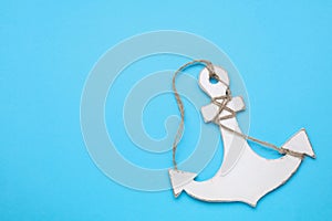 White wooden anchor figure on light blue background, top view. Space for text